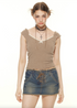A woman wearing a tan cable-knit crop top with studded choker stands facing camera in lace-up denim mini skirt against white background