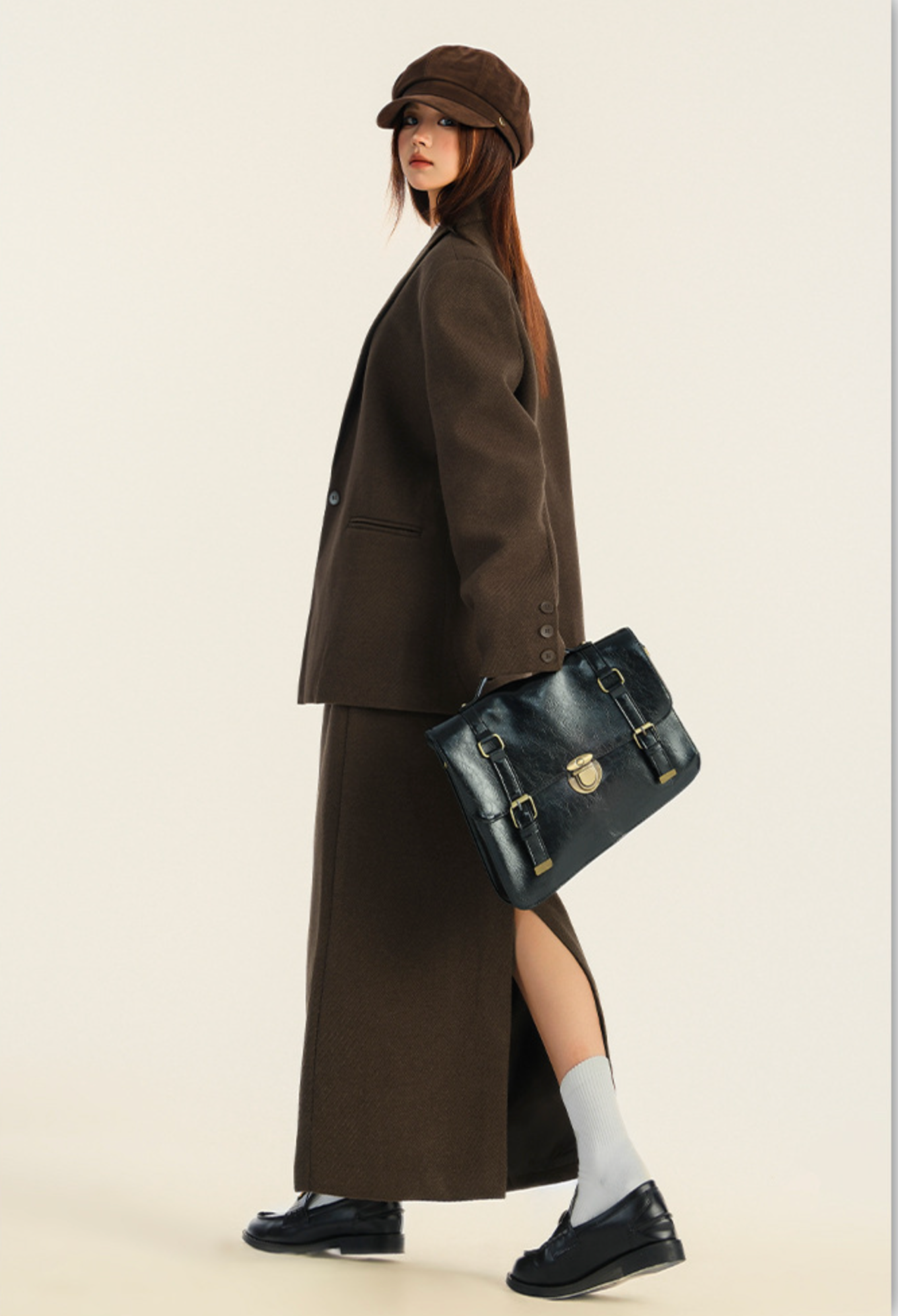 Side view highlighting skirt slit and blazer silhouette, paired with black leather satchel
