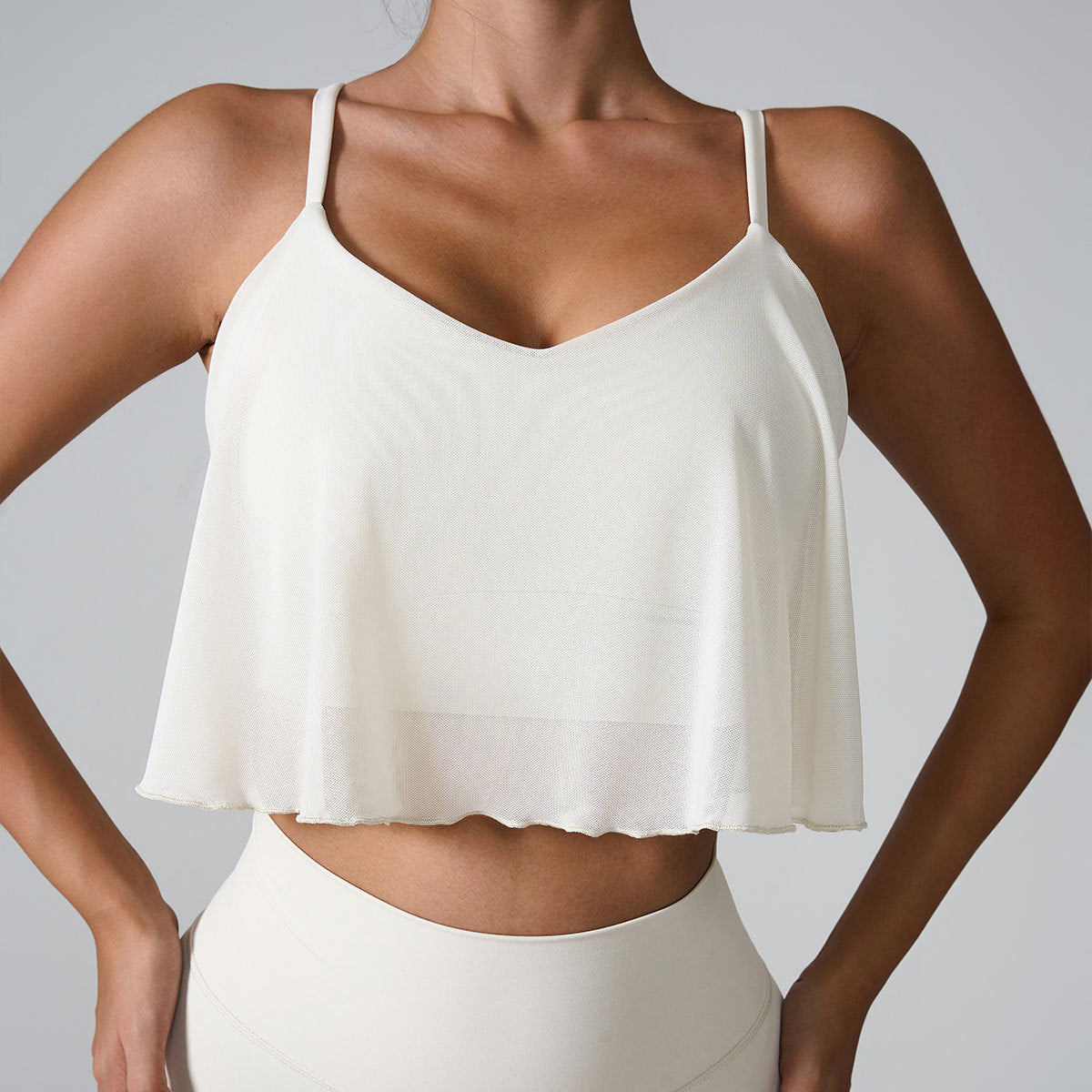 Close-up of white cropped camisole showing V-neckline and flowing fabric detail