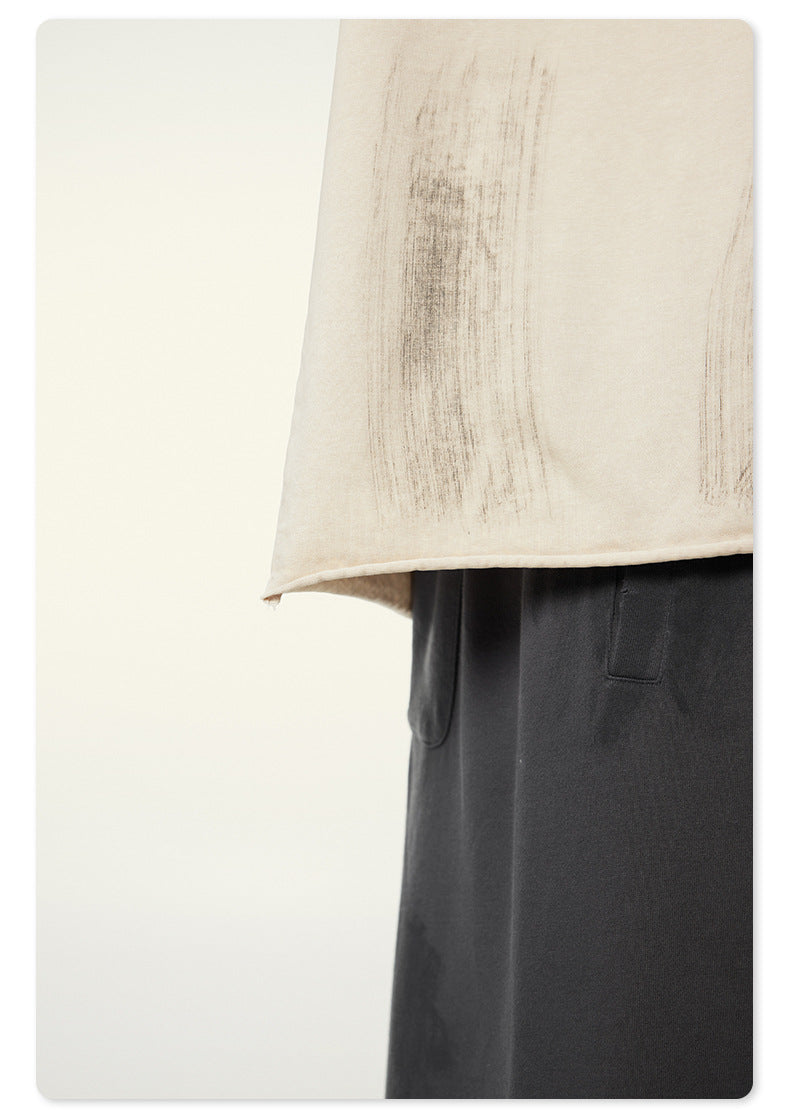 Hem detail of off-white t-shirt against charcoal gray pants
