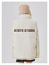 Back view of cream puffer jacket with brown NEIGTR STUDIO text across shoulders, worn with beige knit beanie against white background