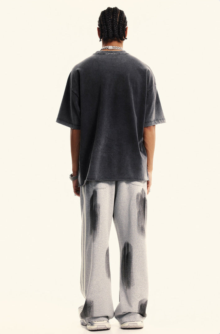 Back view of model showing charcoal oversized t-shirt and gray tie-dye sweatpants with paint splotch pattern