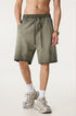 A man wearing olive green washed cotton shorts with drawstring waist, gold watch and white athletic socks against white background