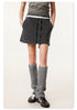 Close-up of black mini skirt on model showing side pocket detail and paired with gray ribbed leg warmers