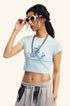 Light blue cropped t-shirt with a blue devil girl and snake graphic, styled with gray sweatpants and bold accessories
