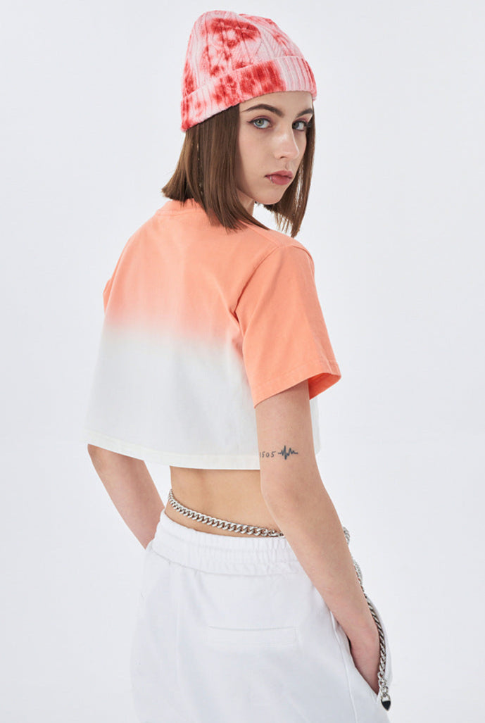 Profile of model in coral ombré crop top, tie-dye beanie, layered necklaces