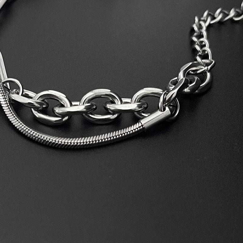 Detailed shot of chain links and snake chain accents on a silver bracelet, highlighting its layered and textured design.