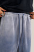 Detail of light blue sweatpants elastic waistband with drawstring cord and ring detail
