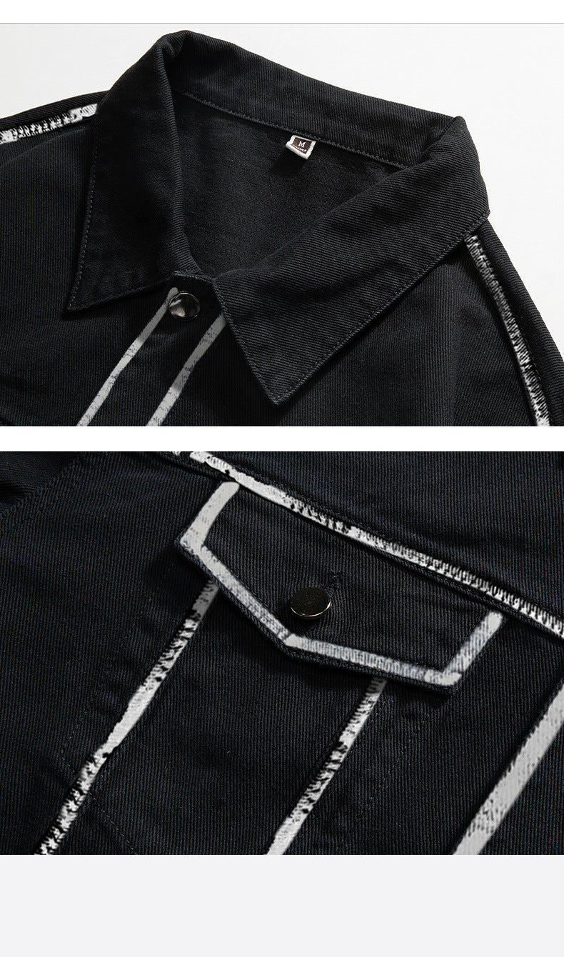 Close-up detail of black denim jacket showing collar and chest pocket with white outline stitching and metal button closure
