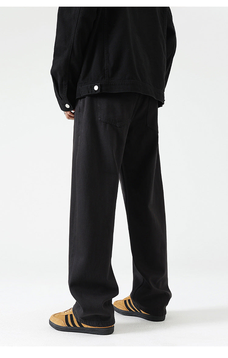 Black wide-leg jeans with relaxed fit, shown with jacket hem and tan suede sneakers
