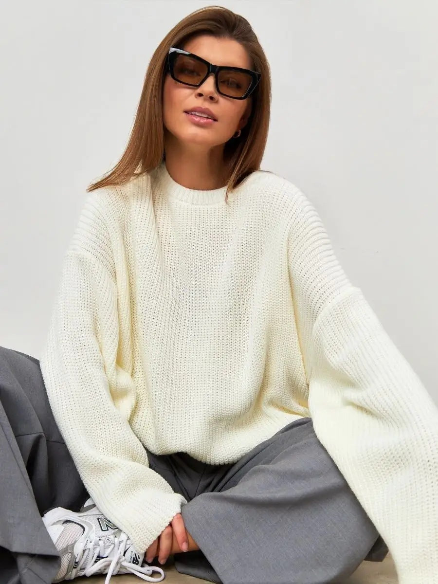 Woman in cream ribbed sweater with sunglasses against wood paneling, casual pose