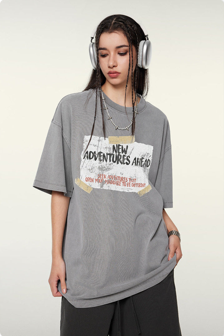Close-up of gray t-shirt with motivational "New Adventures Ahead" text design and silver chain necklace