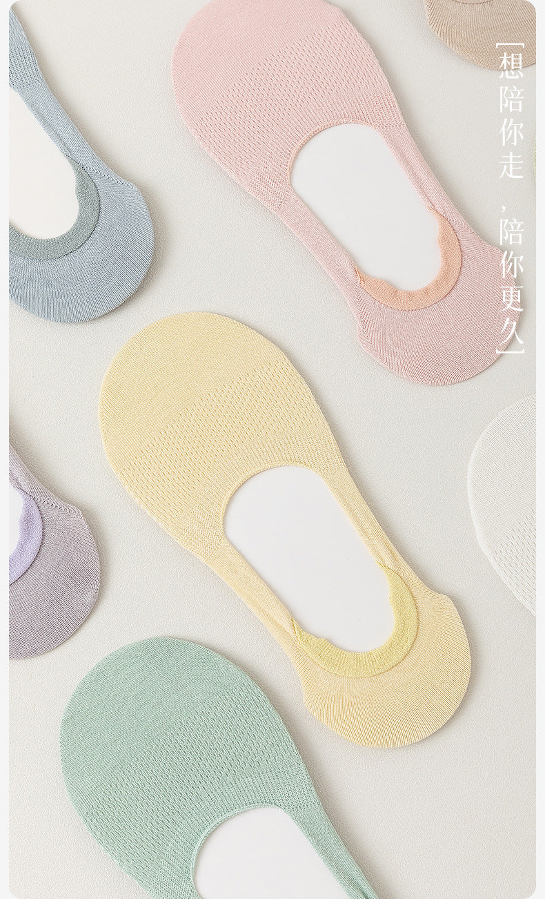 Close-up of knit mesh pattern on no-show socks in soft pastel colors against white background