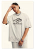 Model in cream Backstairs t-shirt with hand on forehead, silver chain necklace, ring and watch visible, distressed logo print against white background