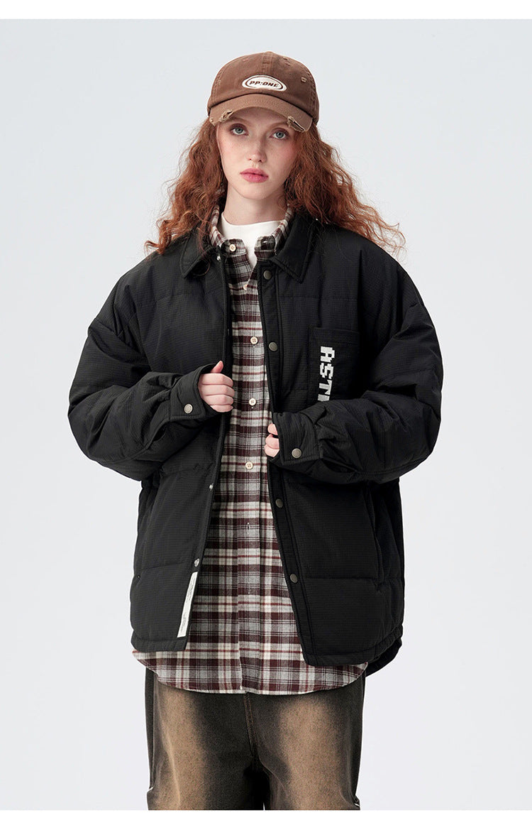 Model in black ASTROSMASH puffer jacket styled with plaid shirt, brown baseball cap and relaxed-fit pants against neutral background