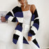 A woman in black, navy and white striped cardigan paired with white tank top and white jeans showcasing relaxed oversized style