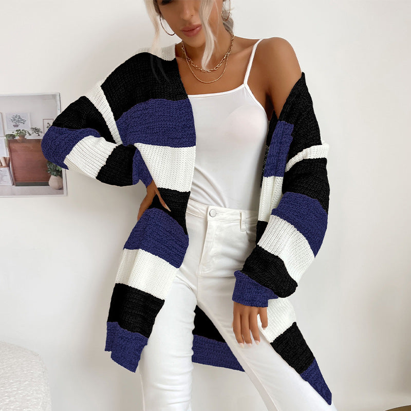 A woman in black, navy and white striped cardigan paired with white tank top and white jeans showcasing relaxed oversized style