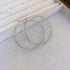 Silver thin hoop earrings on textured fabric background