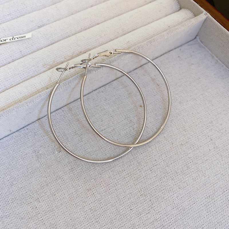 Silver thin hoop earrings on textured fabric background