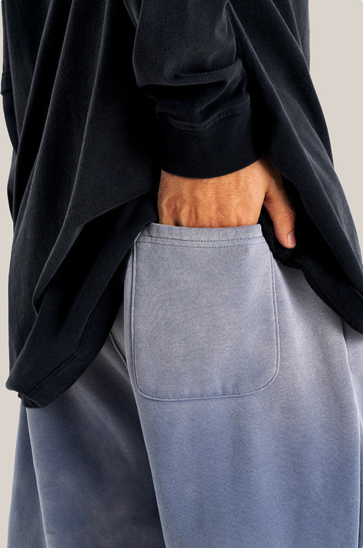Person with hand in back pocket of light blue sweatpants wearing oversized black hoodie