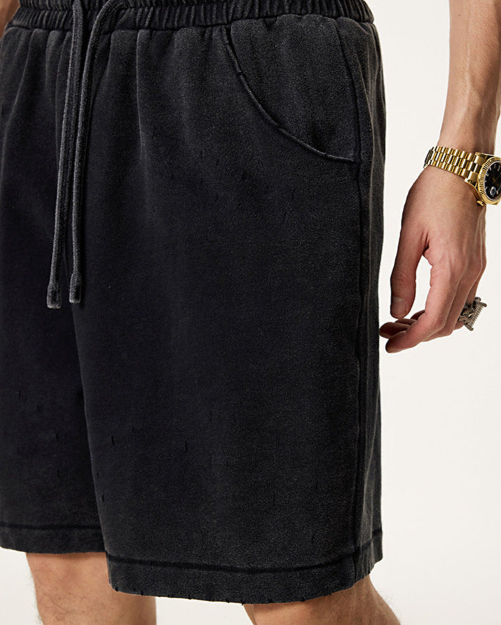 Close-up of black washed shorts featuring an elastic waistband, drawstring, and side pocket detail
