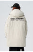A woman showing back view of cream Be_Born Beacaac parka with brand logo lettering while wearing black cap against white background