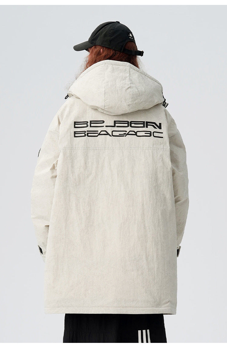 A woman showing back view of cream Be_Born Beacaac parka with brand logo lettering while wearing black cap against white background