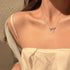 Silver bow necklace with crystals worn with cream off-shoulder top in sunlight