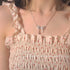 Crystal bow necklace paired with white cherry-print smocked dress with ruffle details