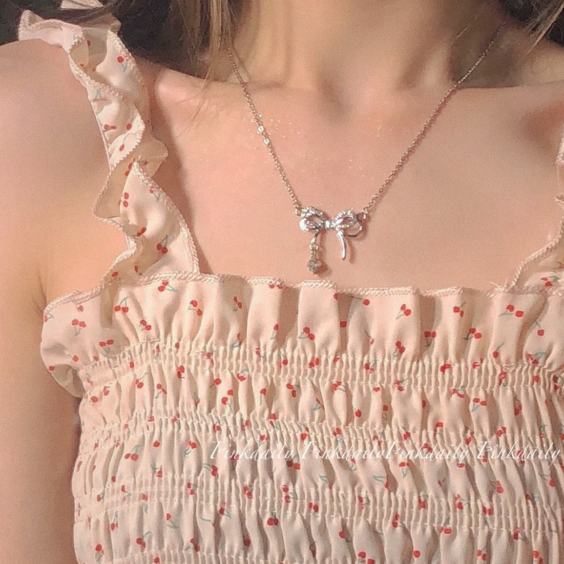 Crystal bow necklace paired with white cherry-print smocked dress with ruffle details