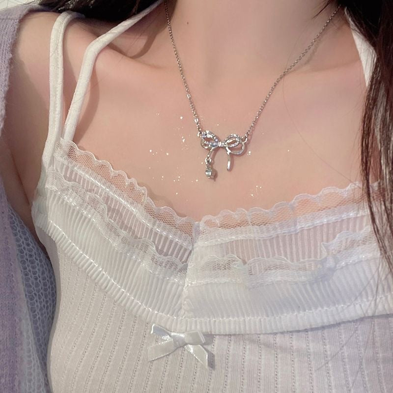Silver crystal bow necklace styled with white lace-trimmed camisole