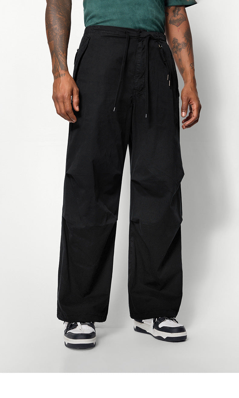 A close-up of black wide-leg pants with drawstring details, worn by a model