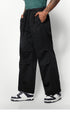 A side view of black wide-leg pants with deep pockets, paired with black-and-white sneakers