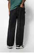 A rear view of black wide-leg pants featuring a back pocket, worn by a model in a green T-shirt