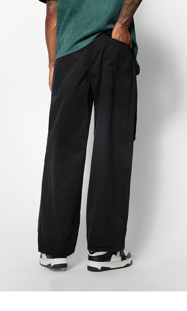 A rear view of black wide-leg pants featuring a back pocket, worn by a model in a green T-shirt