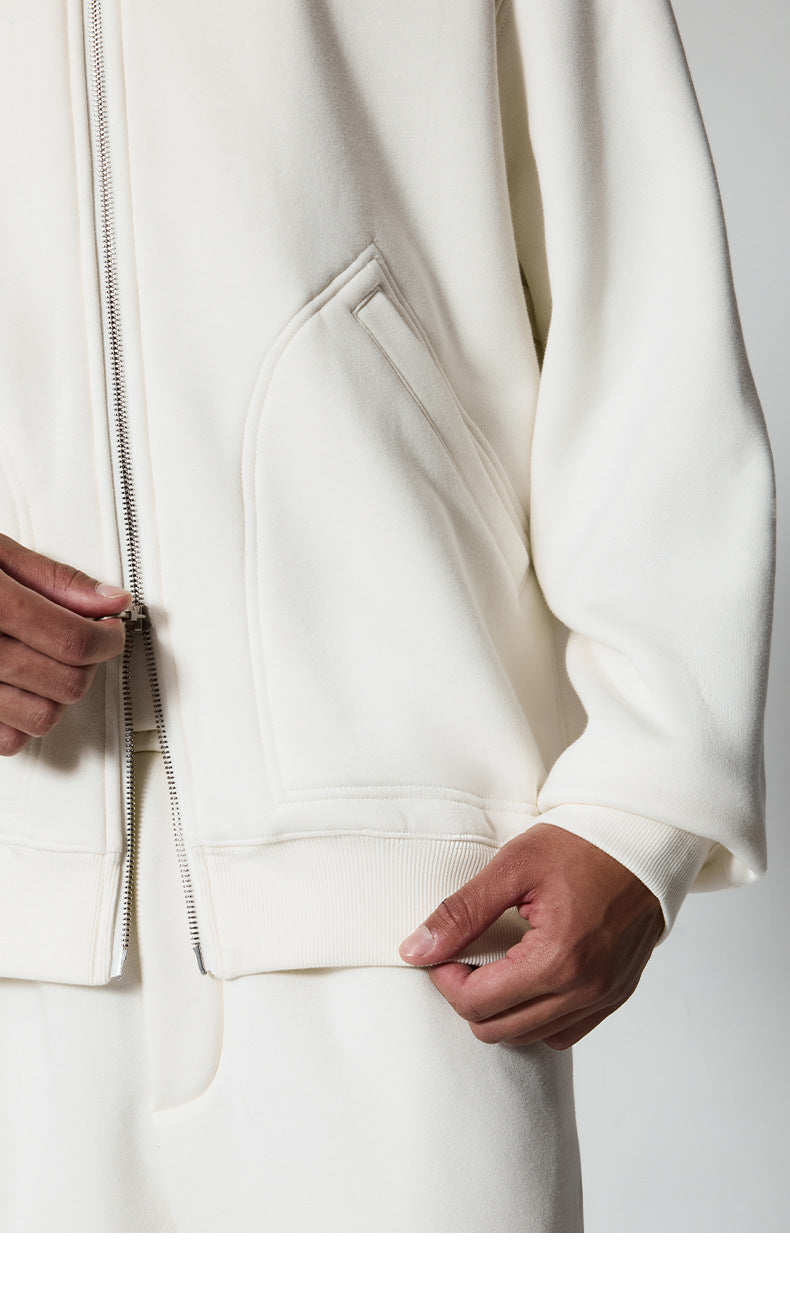 Detail shot of angled pocket design and ribbed hem on white track jacket