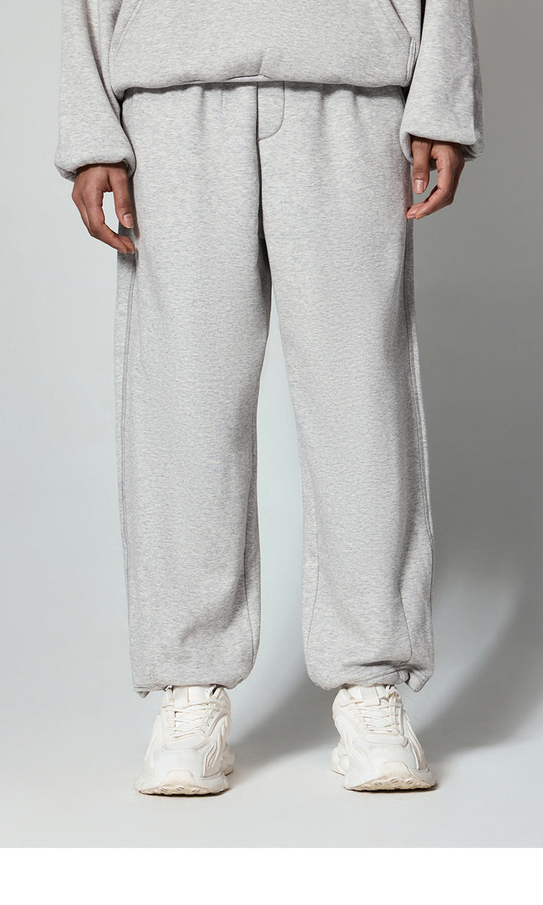 Light gray sweatpants with elastic waistband, paired with white chunky sneakers, shown from waist down