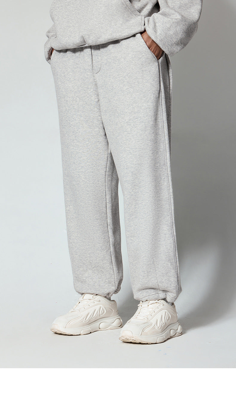 Gray sweatpants with side pockets, styled with white chunky sneakers, photographed from waist down