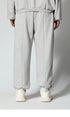 Detailed view of light gray sweatpants with center seam and elasticated bottom, showcasing relaxed fit