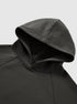 A close-up of a dark gray hoodie’s hood and shoulder seam, laid flat on a light gray background