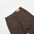 Back view detail of dark brown pants with patch pockets and brand label, photographed on white background