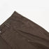 Fabric detail of brown utility pants showing diagonal seam construction and twill texture on white surface