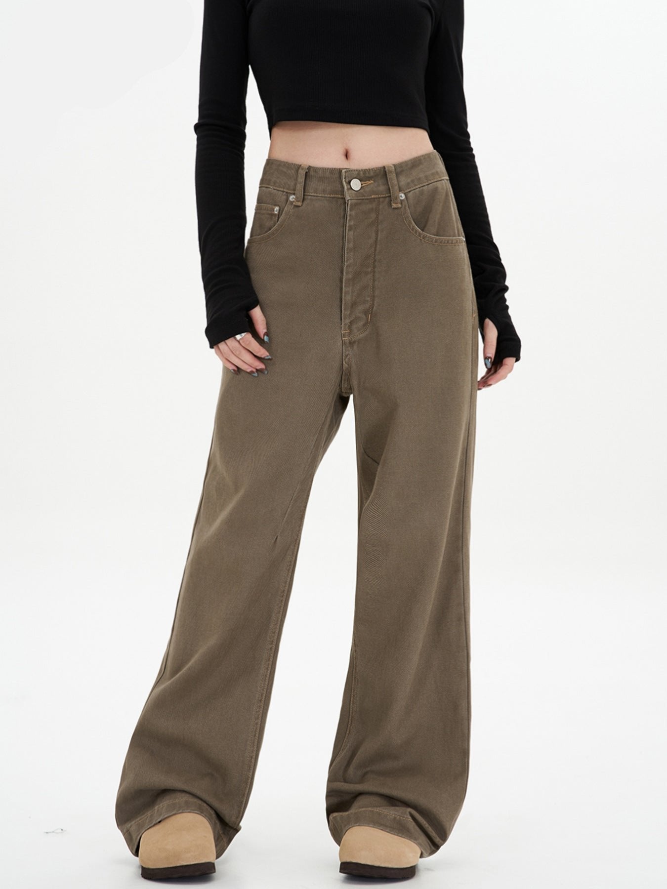 A woman standing wearing high-waisted olive-brown wide-leg pants with classic 5-pocket styling, paired with a black crop top and beige platform boots