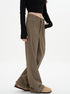 A woman wearing olive-brown wide-leg pants with her hand in pocket, black long-sleeve crop top, and beige platform boots shown from side angle