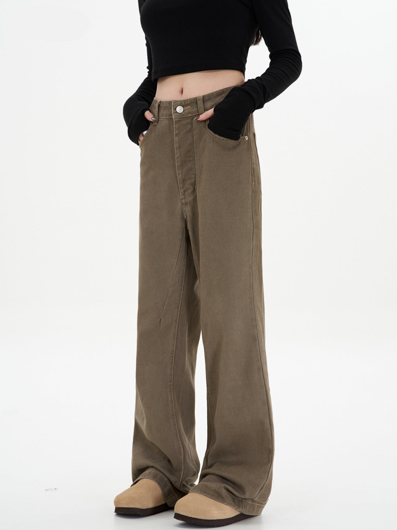 A woman with hands in pockets modeling olive-brown wide-leg pants with high waist, black crop top with thumb holes, and beige platform boots