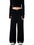 A woman standing in black wide-leg pants with high waist, black long-sleeve crop top, and white sneakers shown from front