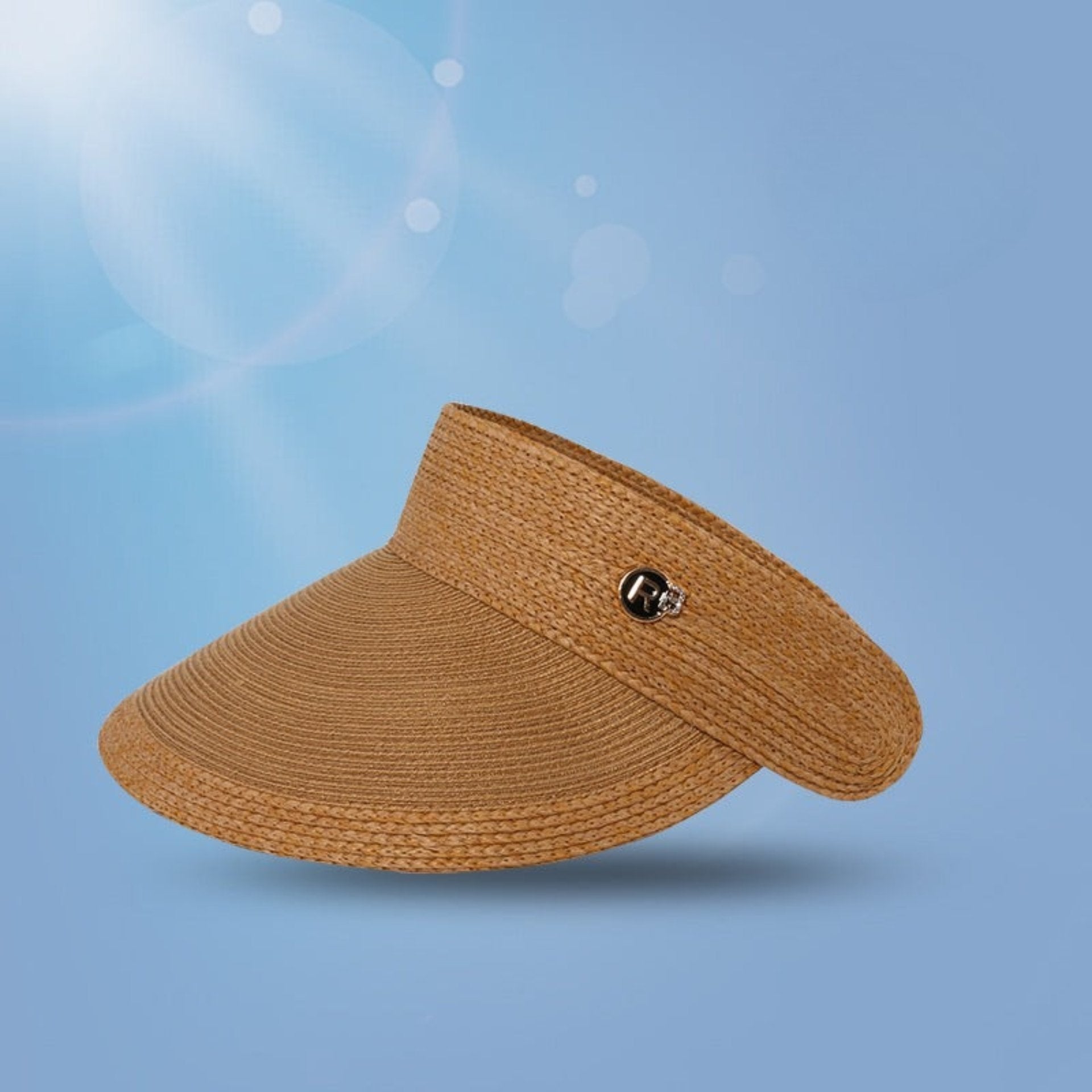 A deep brown woven straw visor with a wide brim, adorned with a logo charm and UV protection certification.