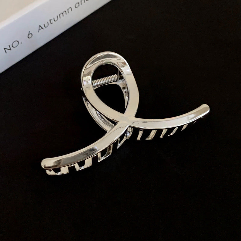  A sleek silver acrylic hair claw with a reflective glossy finish, set against a black background.
