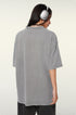 Back view of woman in gray oversized t-shirt with silver headphones showing relaxed fit silhouette