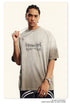 Model wearing Breaking Tradition beige oversized t-shirt with metal-inspired logo, accessorized with silver jewelry